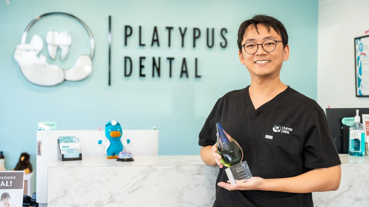Dr Terry Pu holding up their b corp trophy