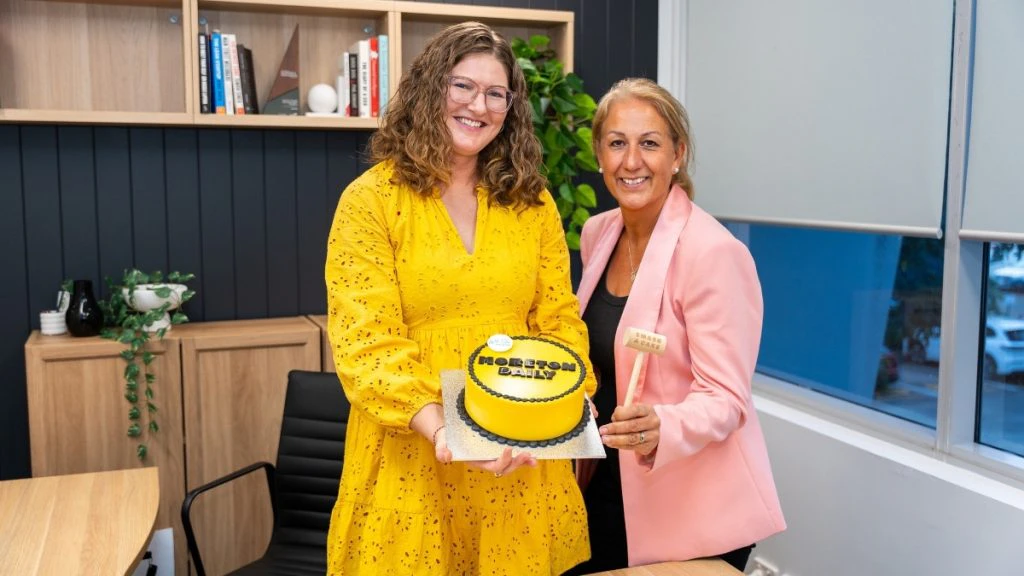 Web-Sta Web Design's Karen Ahl holding a smash cake with Moreton Daily Group's Lyndsay Lawler